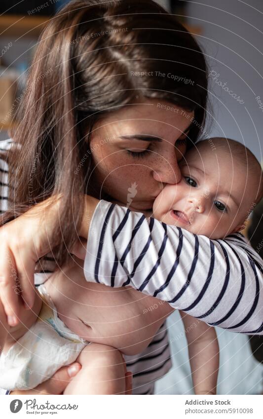 Tender moment between mother and newborn baby kiss tender love affection peace care gentle woman child infant embrace soft light room quiet family bonding