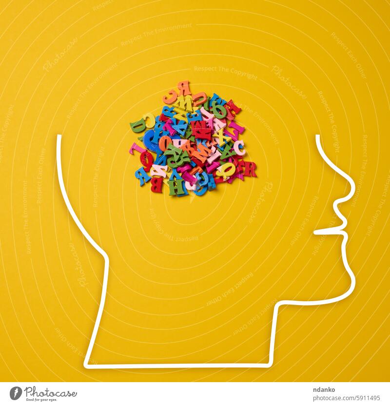 The silhouette of a head on a yellow background, outlined by a white line. Inside the head are many multi-colored letters thoughts ideas information