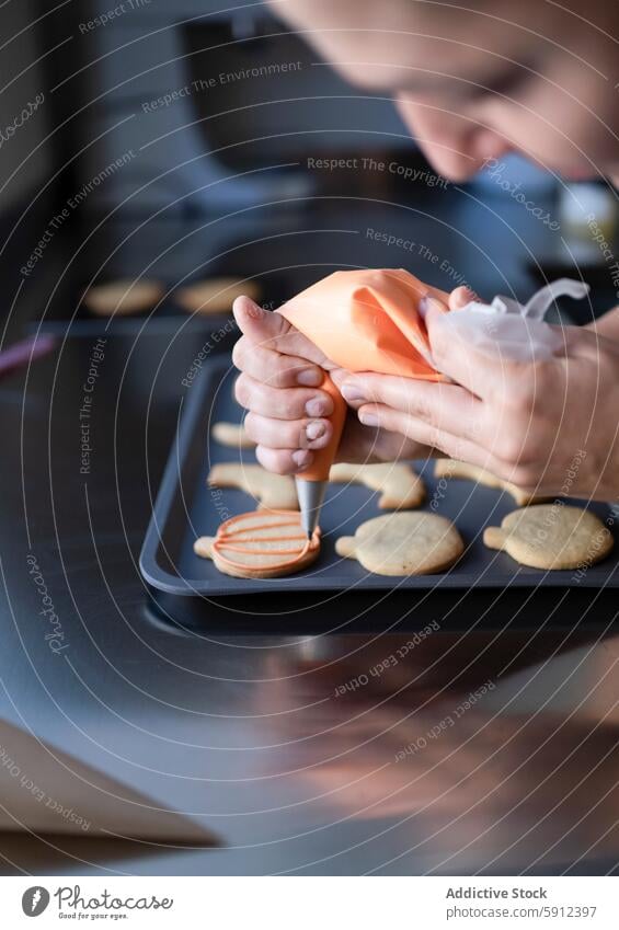 Decorating homemade Halloween cookies on a kitchen counter halloween decoration baking countertop icing orange person hand gesture creativity food celebration