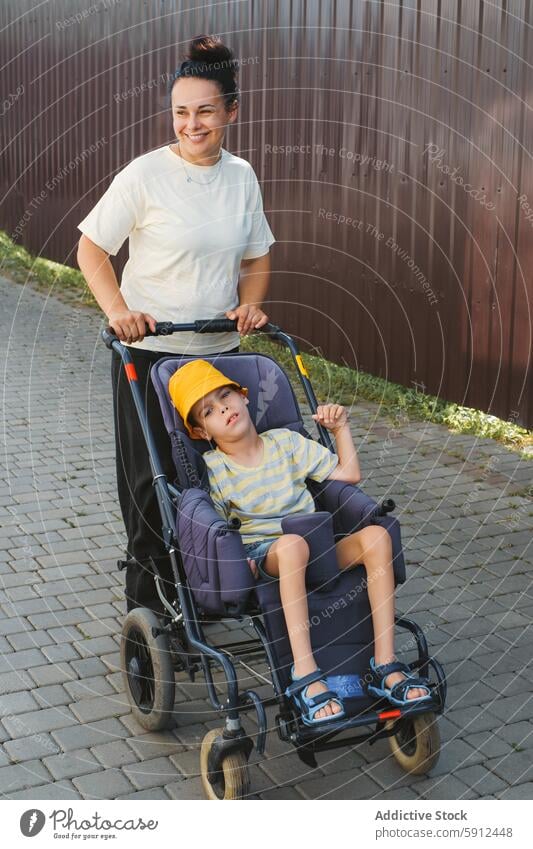 Mother walking with son with cerebral palsy in wheelchair mother disability outdoor care bond support mobility parental support stroll pathway summer sunny