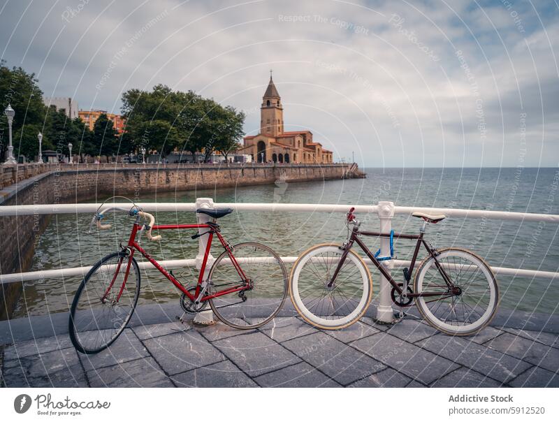 Coastal cycling in Gijon with church backdrop gijon spain bicycle waterfront railing iglesia de san pedro coastal city travel tourism outdoor leisure bike