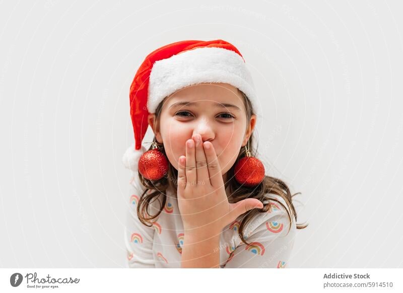 Young girl in Santa hat with Christmas ornaments as earrings santa hat christmas joy laughter festive holiday celebration winter december cheerful child youth