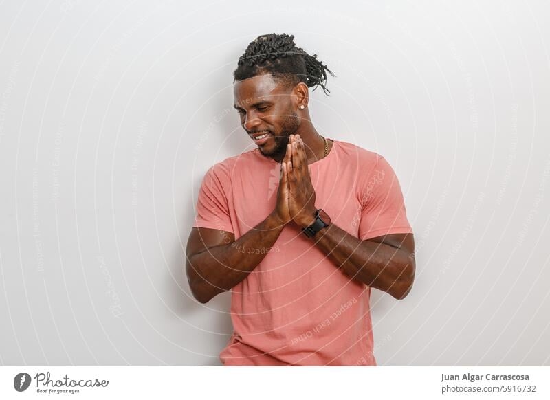 Smiling Man in Pink Shirt With Braided Hair Posing Against White Wall man pink shirt braided hair smile gratitude casual African American positive energy