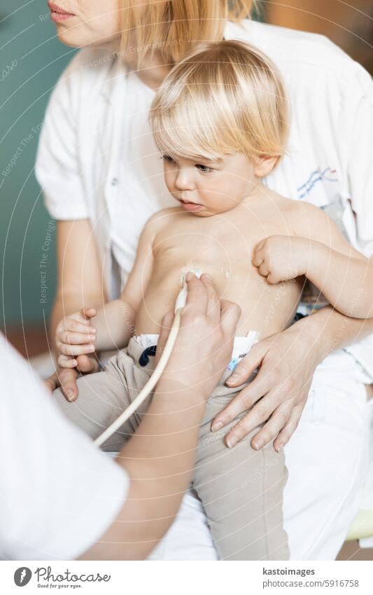 Small child being checked for heart murmur by heart ultrasound exam by cardiologist as part of regular medical checkout at pediatrician. medicine healthcare