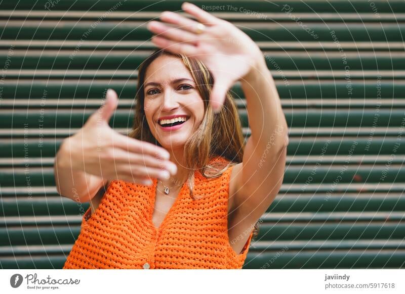 Woman framing with hands smiling at camera latin woman urban portrait frame city urban lifestyle happiness joyful confidence positive expression chic