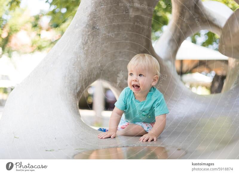 Child playing on outdoor playground. Toddler plays on school or kindergarten yard. Active kid on stone sculpured slide. Healthy summer activity for children. Little boy climbing outdoors.