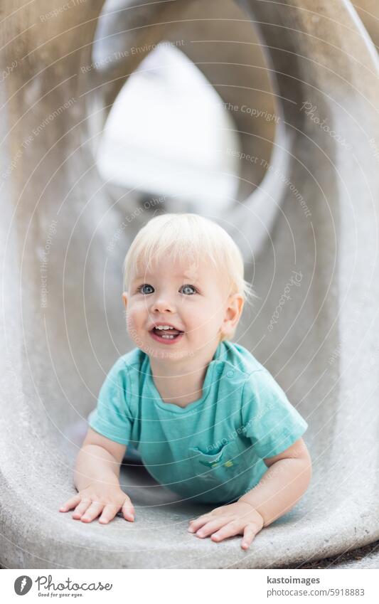 Child playing on outdoor playground. Toddler plays on school or kindergarten yard. Active kid on stone sculpured slide. Healthy summer activity for children. Little boy climbing outdoors.