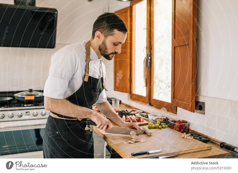 Private chef preparing sausages in kitchen, focusing on task private chef man cooking chopping ingredients preparation home culinary gourmet food apron