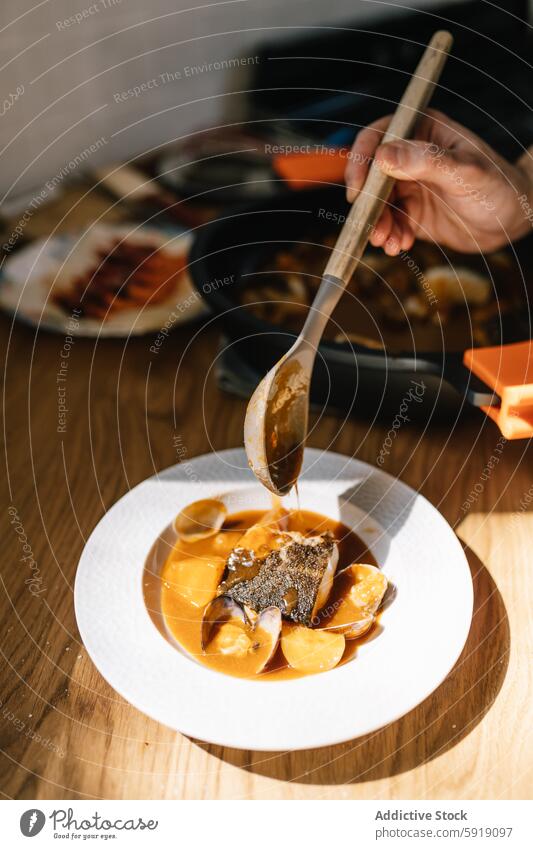 Private chef pours sauce over elegant dish in sunlit room private chef kitchen sunlight sauce pouring seafood dish fish fruit food plating modern kitchen