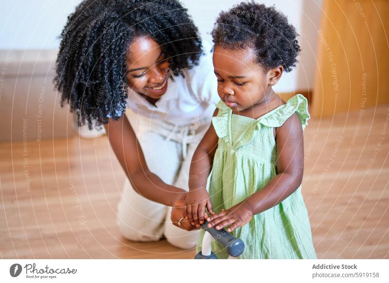 African American mother teaches daughter to walk indoors african american black ethnic family toddler woman child parenting teaching walking support bonding