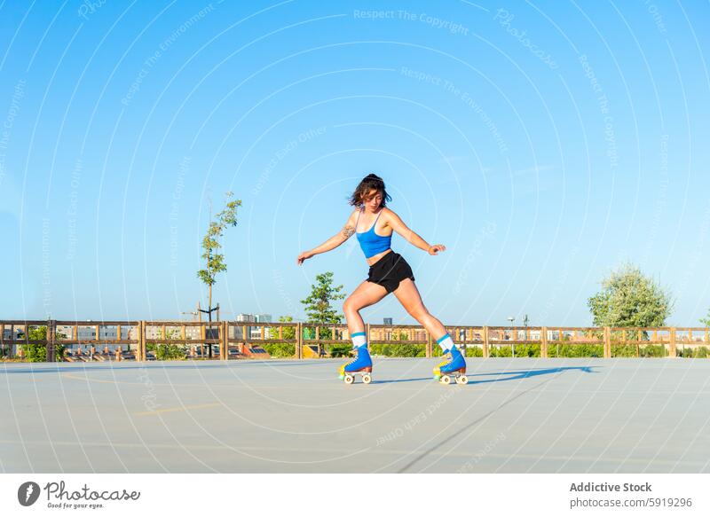 Young woman roller skating in a sunny outdoor skate park blue sky activity sport roller skates balance skill athletic wear summer recreation leisure youth