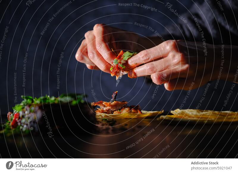 Woman adding toppings to rib tacos on a dark table woman hand garnish herb rustic flavor meal food cuisine cooking preparation fresh assembling process