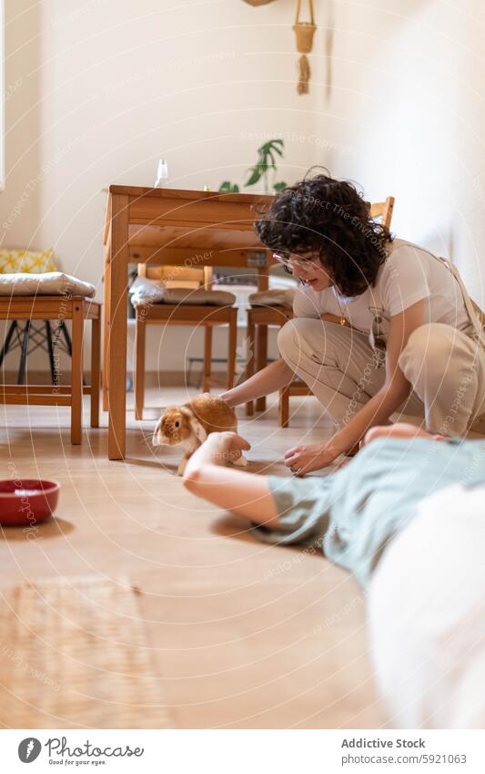 Lesbian couple of women caressing cute bunny at home lesbian stroke together domestic lgbt female homosexual same sex pet animal love tender rabbit adorable