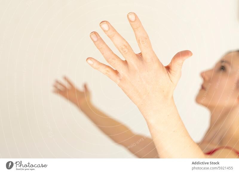 Woman outreaching hand with blurred face in background woman gesture movement graceful caucasian close-up soft focus finger skin nail human motion reaching out