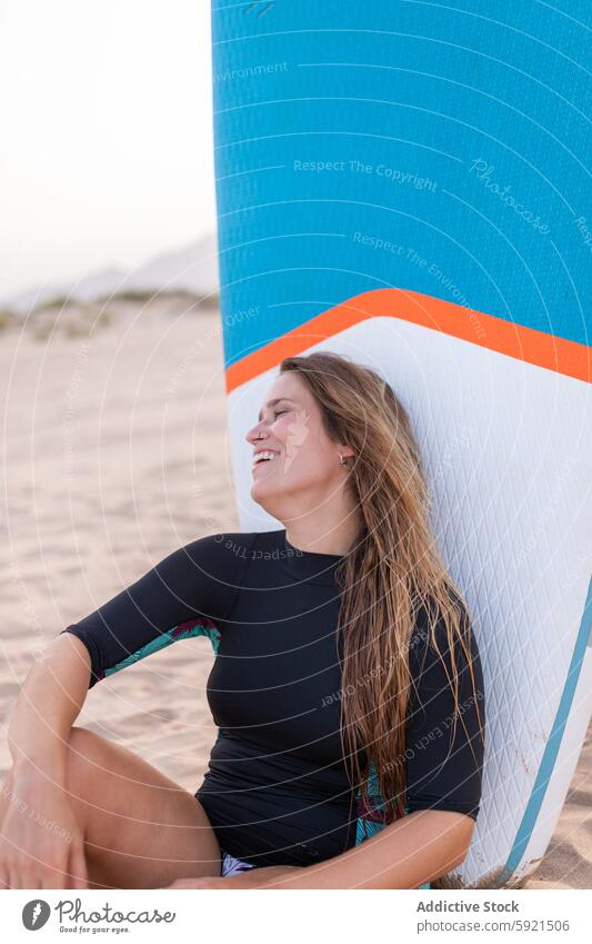 Happy surfer with paddleboard on beach woman sup board seashore seaside summer smile female surfboard cheerful sit glad sand vacation recreation coast blue