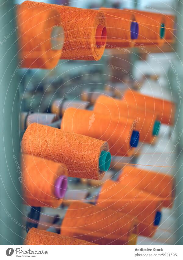 Close-up view of textile yarn spools in a factory setting machinery production industry thread orange vibrant close-up textile industry manufacturing equipment