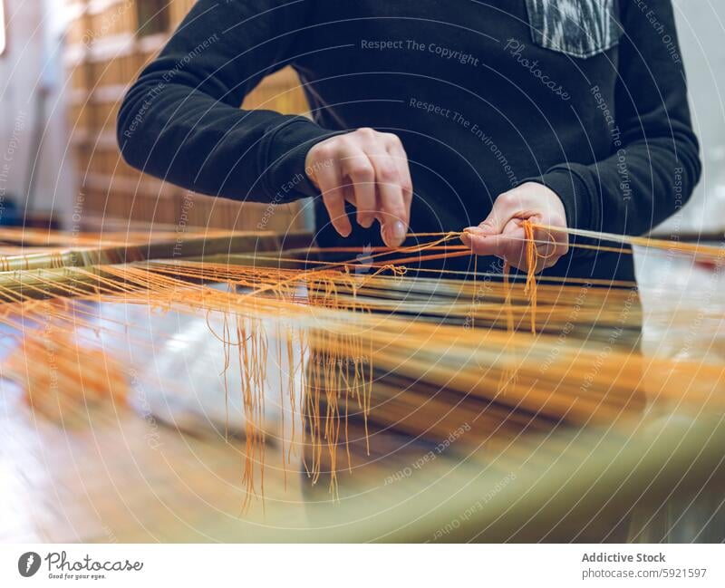 Artisanal weaving process in textile workshop artisan yarn loom traditional manual factory worker hands close-up thread craft skill fabric production industry