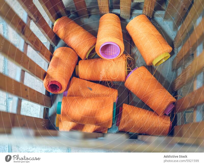 Vibrant orange yarn spools in industrial setting textile factory material thread fiber fabric production manufacture crafting knitting colorful vibrant cotton