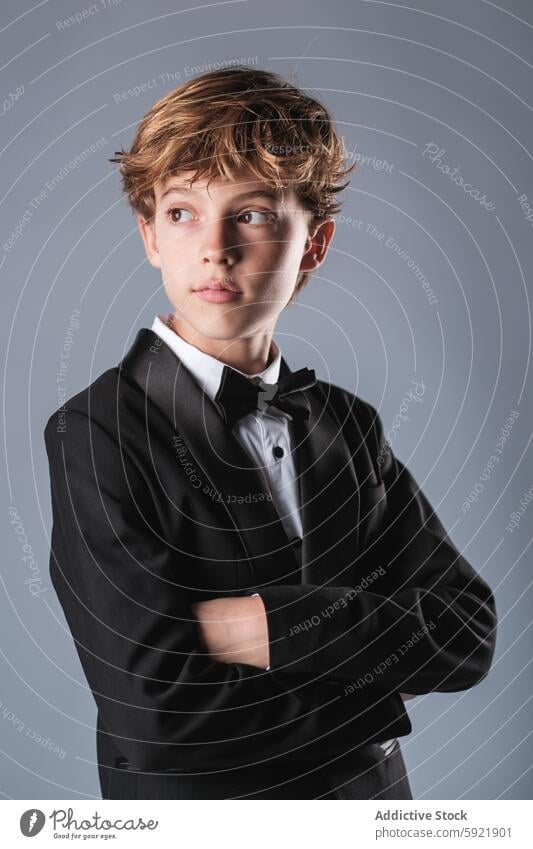 Preteen boy wearing elegant suit and bow tie looking away in studio portrait kid classy confident preteen child style tuxedo formal outfit well dressed