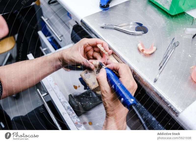 Anonymous dental technician crafting dentures in a laboratory tool work prosthesis close-up dental equipment medical healthcare hands professional craftsmanship