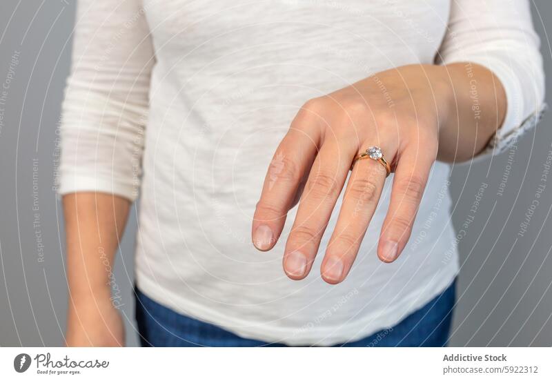 Anonymous close-up of a hand displaying an elegant diamond engagement ring, symbolizing commitment and luxury finger jewelry marriage proposal wedding accessory