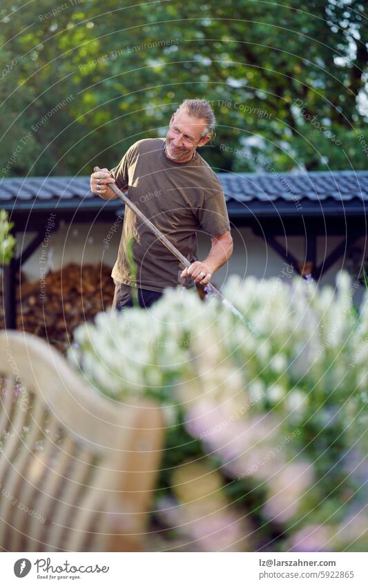 A skilled craftsman engaged in a hands-on outdoor task, carefully raking and maintaining a garden area Craftsman manual labor outdoor work gardening