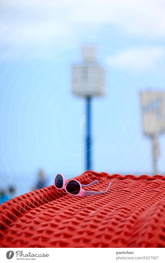 pink sunglasses lie on a red beach shell. Red Beach Ocean vacation Sunglasses Vacation & Travel Sand coast Tourism Sky North Sea blurriness Clock people