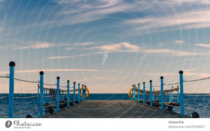 wooden platform with blue posts with ropes and orange lifebuoys on the background of the sea and sky with clouds Egypt Dahab South Sinai Red Sea blue sky