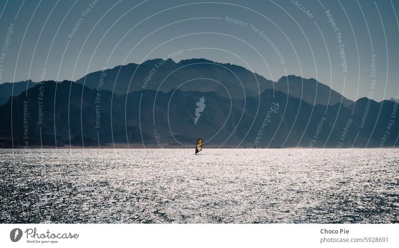 surfer rides in the Red Sea against the backdrop of the coast with high rocky mountains in Egypt Dahab active alone athlete blue color extreme extreme sport