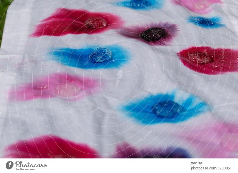 Ice cubes with bright batik colors melt on a white tablecloth Batik Batik dyes Dyeing Colour Cloth splotch of paint White Red Blue Pink Batiks DIY Close-up