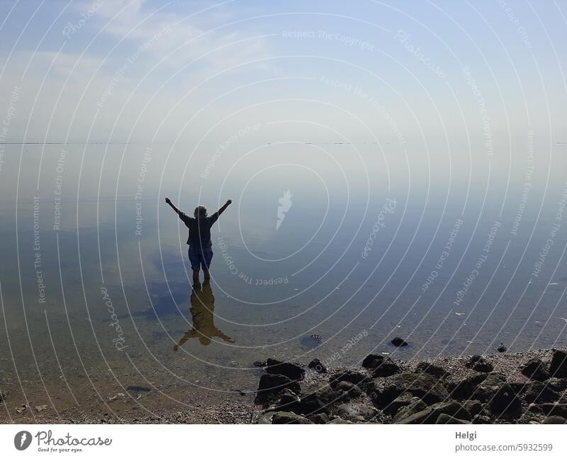 Hallig Gröde | Senior citizen stands in the calm North Sea at low tide and raises her hands to the sky Human being Woman Adults Ocean Water reverberant