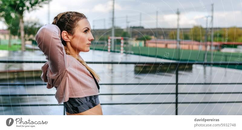 Sportswoman stretching neck and shoulders outdoors panorama sportswoman copy space boxer braids wellbeing arms up back waist up panoramic banner profile athlete