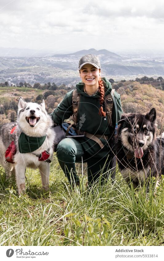 Female hiker with dogs enjoying a mountain hike woman husky trail hiking nature outdoor adventure pet animal landscape scenic view green cloudy hill sport