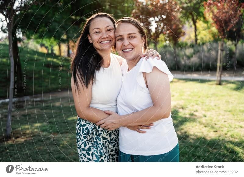 Two lesbian colombian women embracing and smiling in a park with greenery woman couple lgbt embrace smile nature outdoor friendship affection joy happiness love