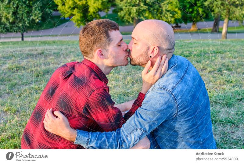 Gay couple sharing a kiss outdoors at sunset gay love affection romantic park green nature summer embrace tender acceptance lgtbiq relationship male hug casual