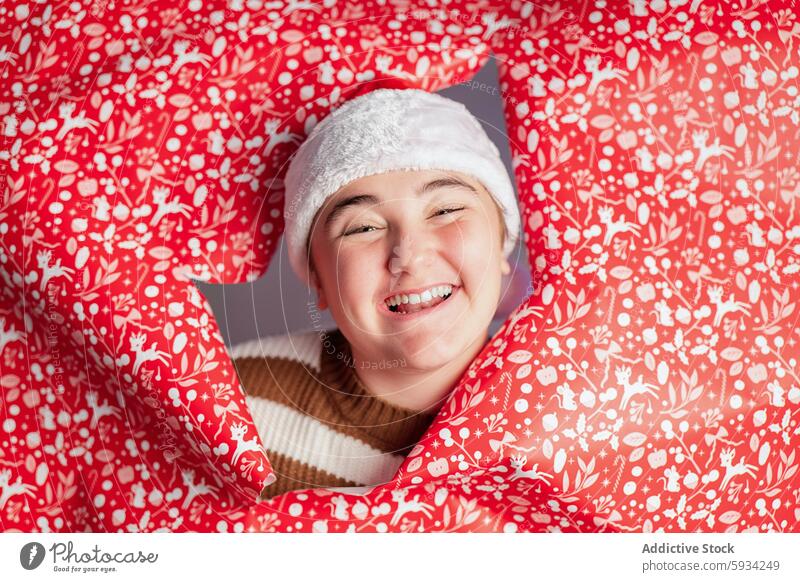 Joyful young person celebrating Christmas with festive decor christmas holiday joy youth smile santa hat red decoration celebration happiness winter season