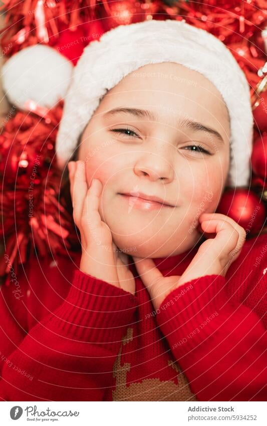 Young girl enjoying festive season dressed in Christmas theme christmas santa hat red sweater decoration spirit holiday cheerful child youth smile happy