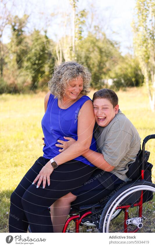 Young boy with cerebral palsy enjoying a moment with mother outdoors wheelchair hug family love affection happy sunny disability care support woman son smile