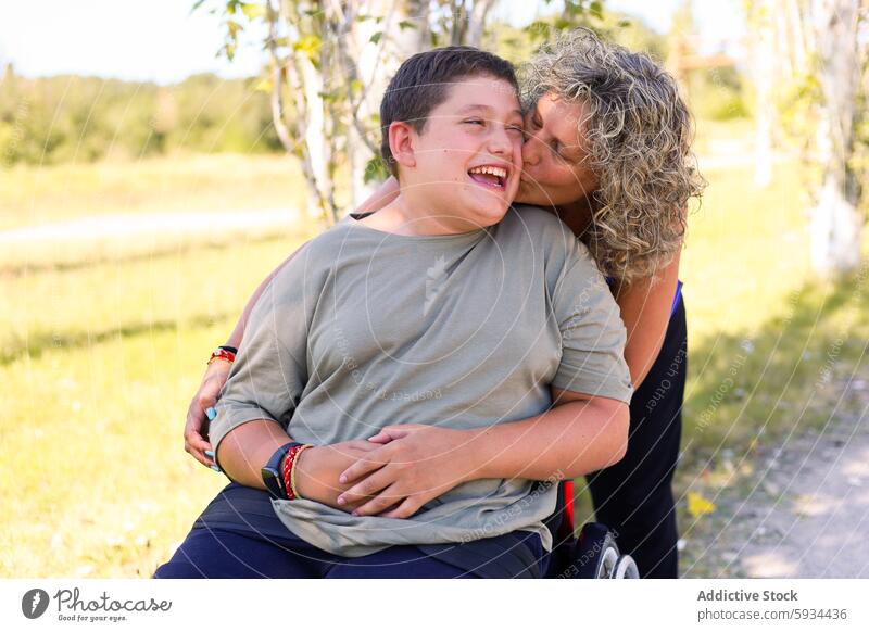 Joyful moment between a mother and her son with cerebral palsy boy disability park love affection wheelchair smile joy care sunny outdoor woman child family