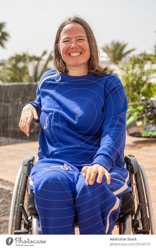 Confident businesswoman in wheelchair smiling outdoors smile confident empowerment accessibility joy tracksuit blue sunny daytime mobility disability