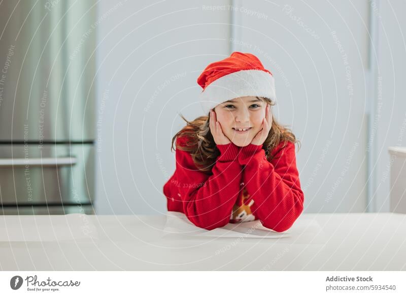 Young girl enjoying Christmas spirit in kitchen christmas santa hat red sweater festive smile holiday december celebration cheerful child winter season happy