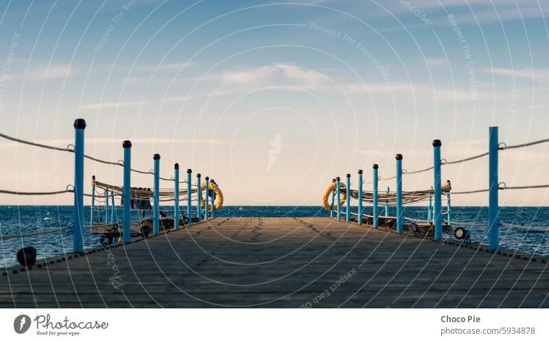 wooden platform with blue posts with ropes and orange lifebuoys on the background of the sea and sky with clouds Egypt Dahab South Sinai Red Sea blue sky