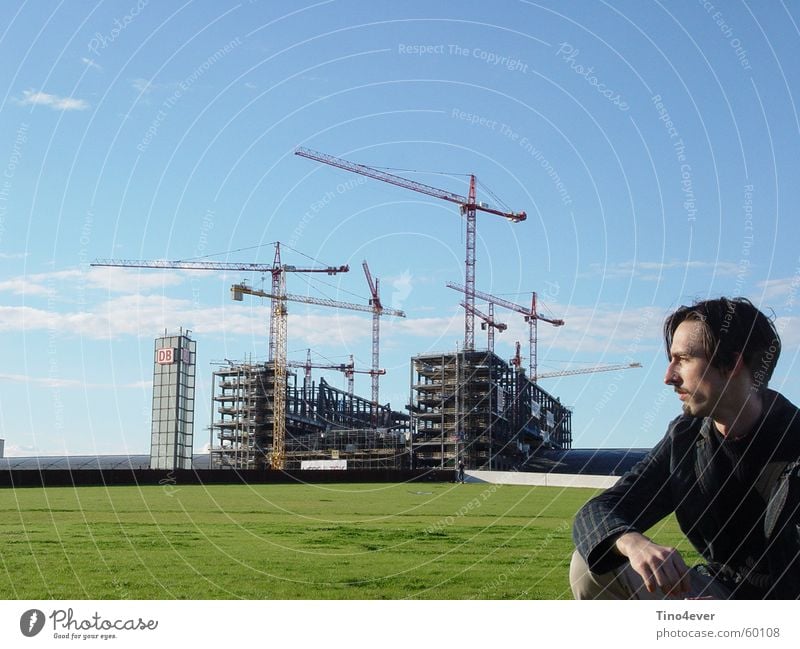 Man in front of Lehrter Central Station Side Grass Meadow Clouds Construction crane Crane Light blue Railroad Train station more teacher Berlin Sky