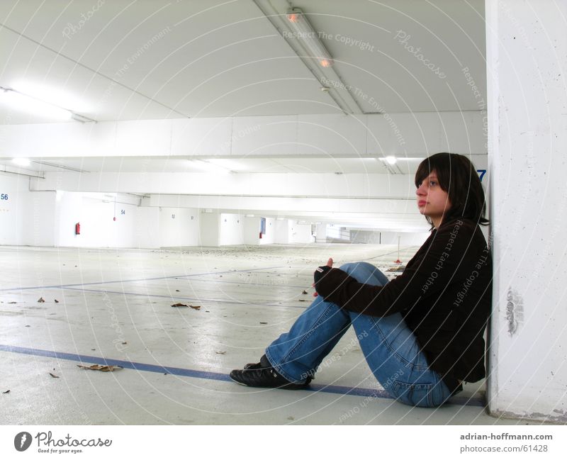 Alone in the underground car park Woman Sit Underground garage Wall (building) Neon light Fluorescent Lights Parking garage Leaf Sterile Future Far-off places