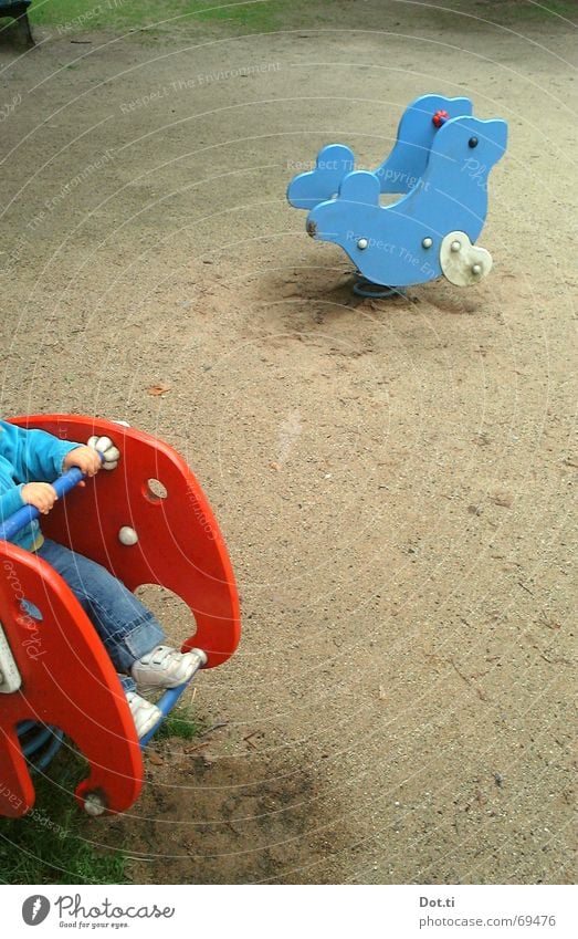 Child on the playground Playground Seesaw Harbour seal Elephant Footprint Boredom Toys Park Toddler Playing To hold on Loneliness Empty Multicoloured Red Joy