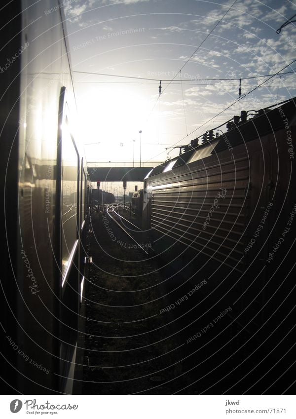 Between the tracks Railroad car Glittering Engines Black Railroad tracks Sunrise Clouds Calm Loneliness Transport Train station Vacation & Travel Technology