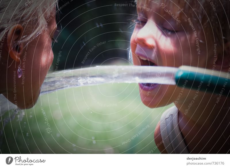 two quench. Two girls are drinking water from a hose that is streaming out. One on the left the other on the right. Drinking Water hose Joy Healthy Life Girl