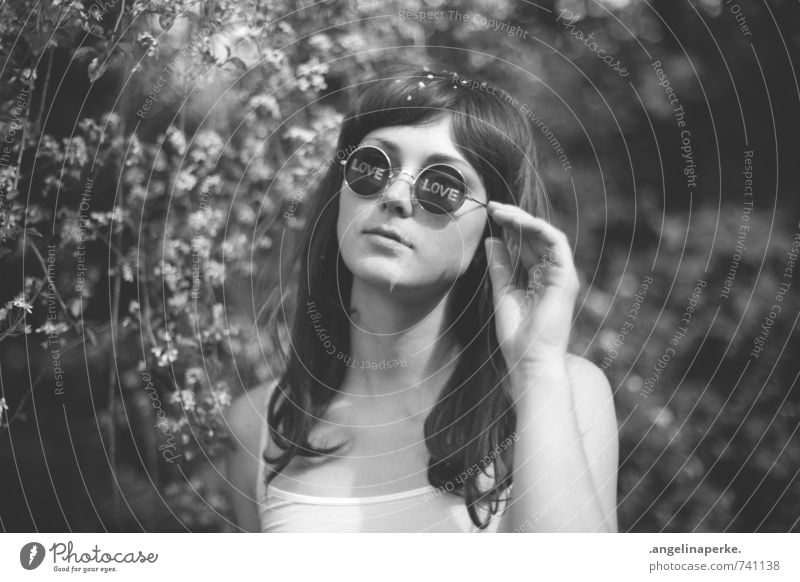 Woman standing under a tree with white flowers, on the lenses of her sunglasses you can read the words "Love" Feminine Youth (Young adults) Human being