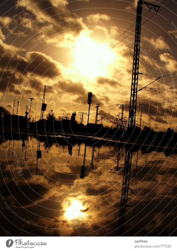 Mirrorun in a puddle Puddle Reflection Back-light Overhead line Electricity Railroad tracks Clouds Dramatic Threat Dark Lateness