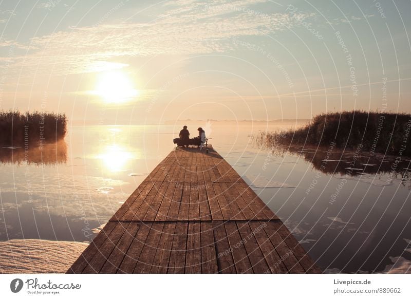 Picnic by the water Winter Human being Young woman Youth (Young adults) Young man Nature Water Sky Sun Sunrise Sunset Lakeside Blue Brown Yellow Orange Pink